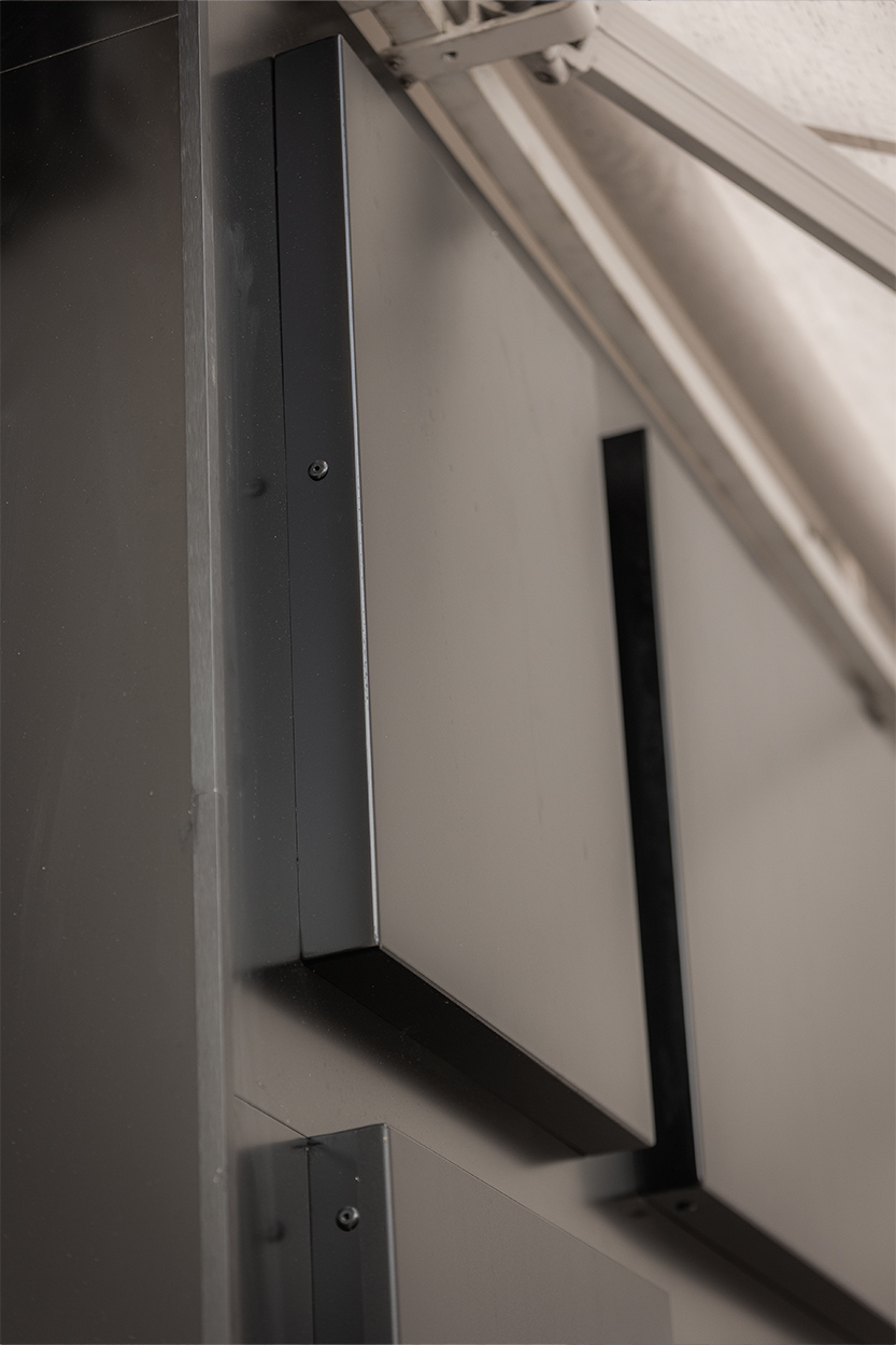 Détail architectural d'un habillage de façade gris avec vitrage, expertise en signalétique extérieure par Griffe Communication à Mont-de-Marsan.