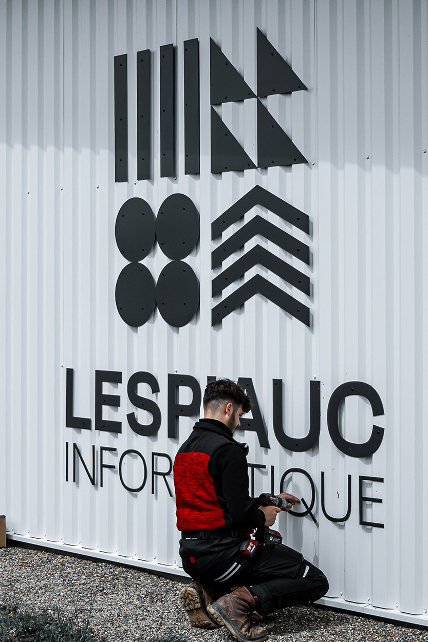 Enseigne en lettrage découpé noir posé sur bardage bois, réalisation de signalétique à Pau par Griffe Communication