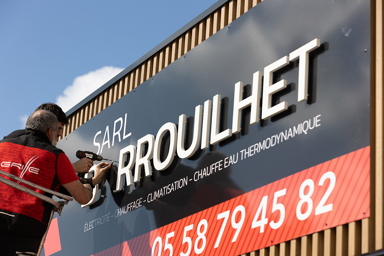Grande enseigne en lettres découpées blanches sur bardage métallique industriel, pose et fabrication à Mont-de-Marsan par Griffe Communication