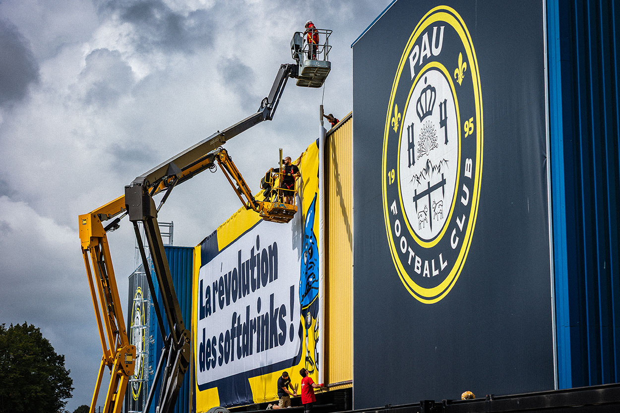 Installation grand format sur nacelles d'enseignes monumentales en toile tendue imprimée pour le stade du Pau Football Club, pose de supports de communication près de Mont-de-Marsan par l'entreprise Griffe Communication
